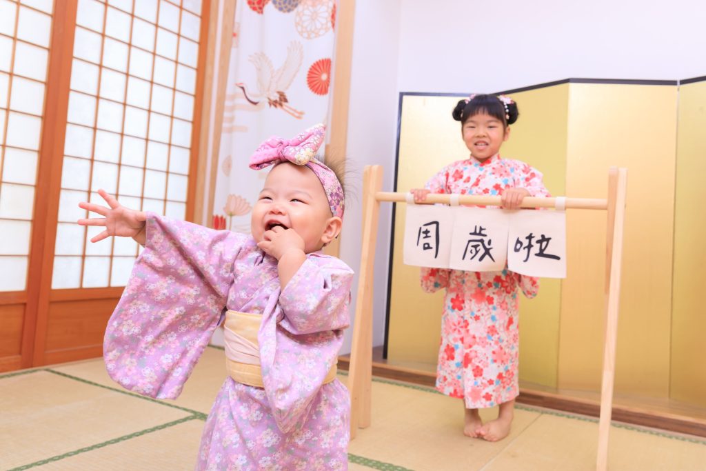 寶寶抓周儀式歡樂瞬間，小女孩穿粉色和服開心揮手，搭配日式場景與祝福氛圍