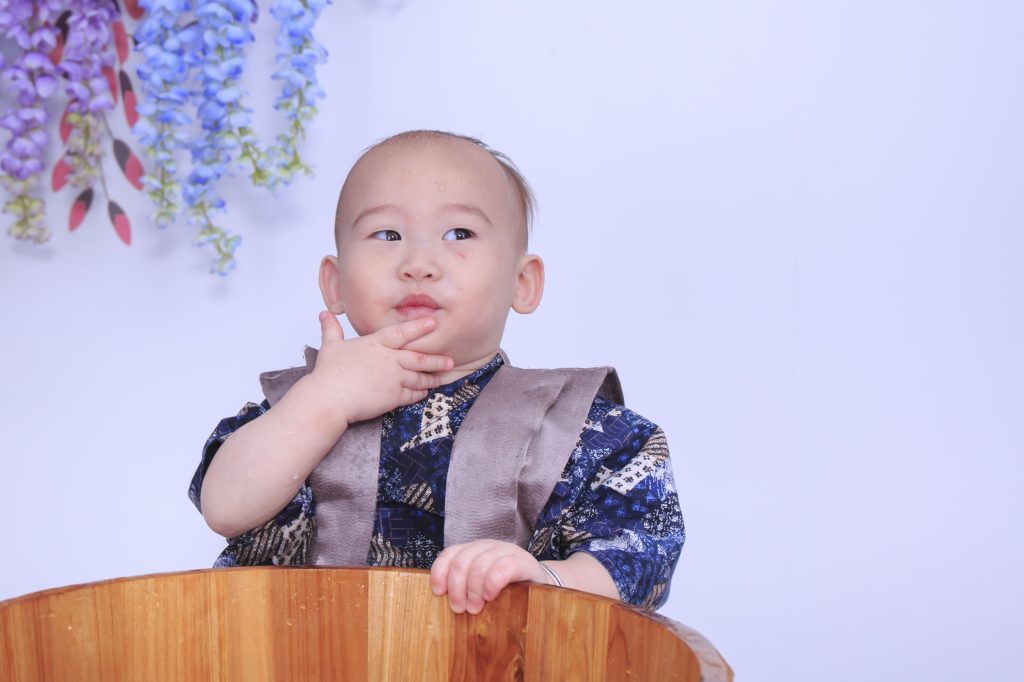 寶寶抓周拍攝現場，小男嬰穿著藍色傳統服裝坐在木桶中，呈現抓周儀式自然互動畫面