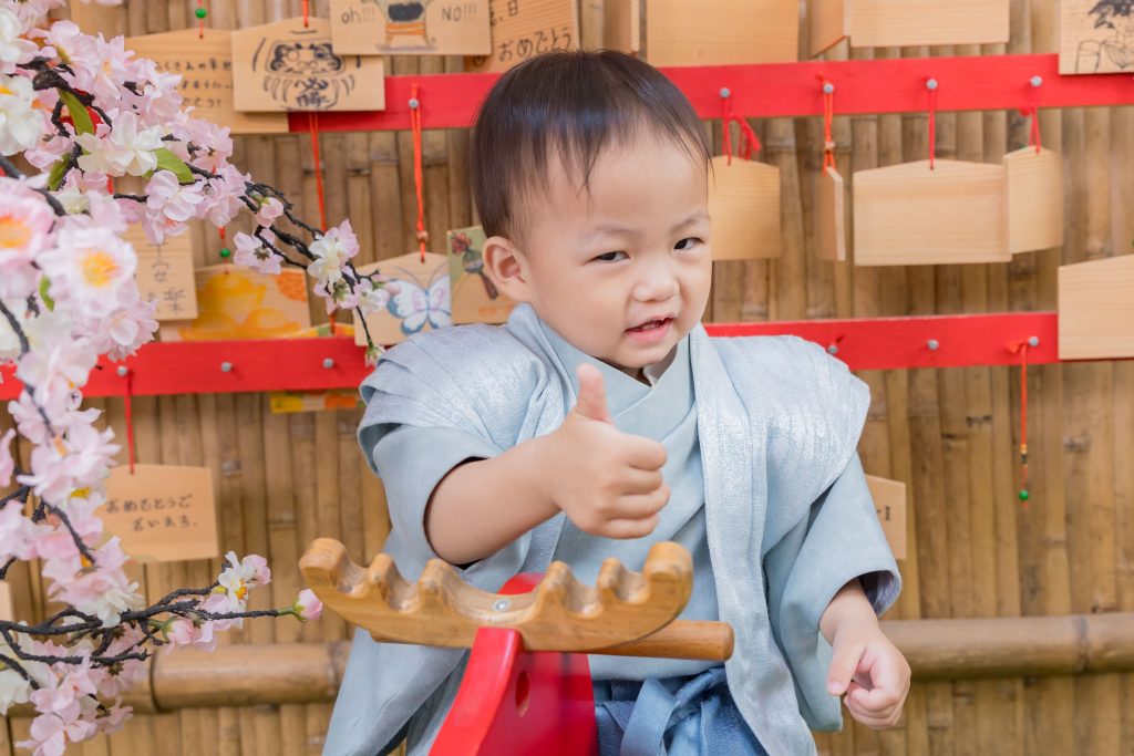寶寶抓周儀式現場，小男嬰穿日式和風服裝，在抓周場景中開心比讚互動