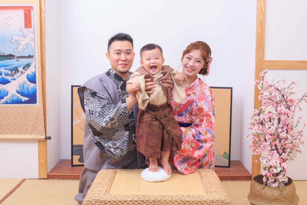 寶寶在家人攙扶下踩踏一升餅祈願步步踏實的儀式畫面
