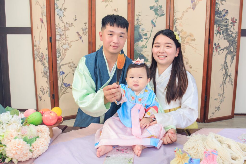 主持人持韓式狀元筆輕拂寶寶額頭祈求學業有成的畫面